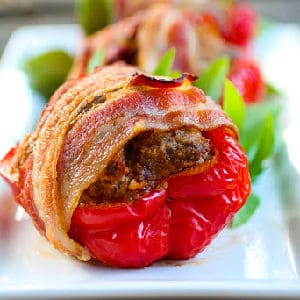 closeup of meatloaf stuffed red bell peppers wrapped in crispy bacon - recipe card image.