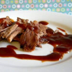 Brisket on a plate with a rich barbecue sauce.