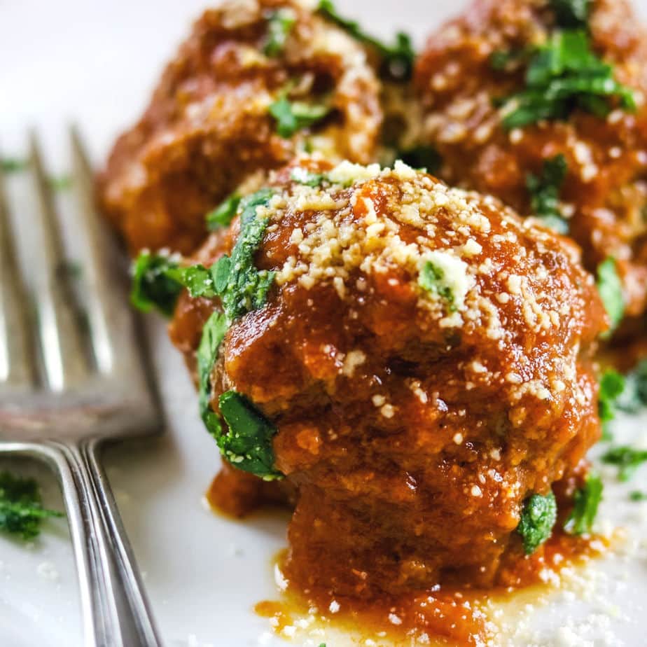 closeup image of meatballs in marinara with parmesan sprinkled on top