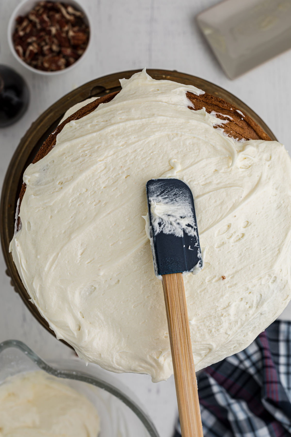 Putting frosting on the cake with a rubber spatula.