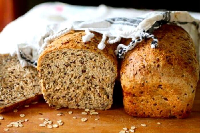 Two loaves of finished bread partially covered in a towel.