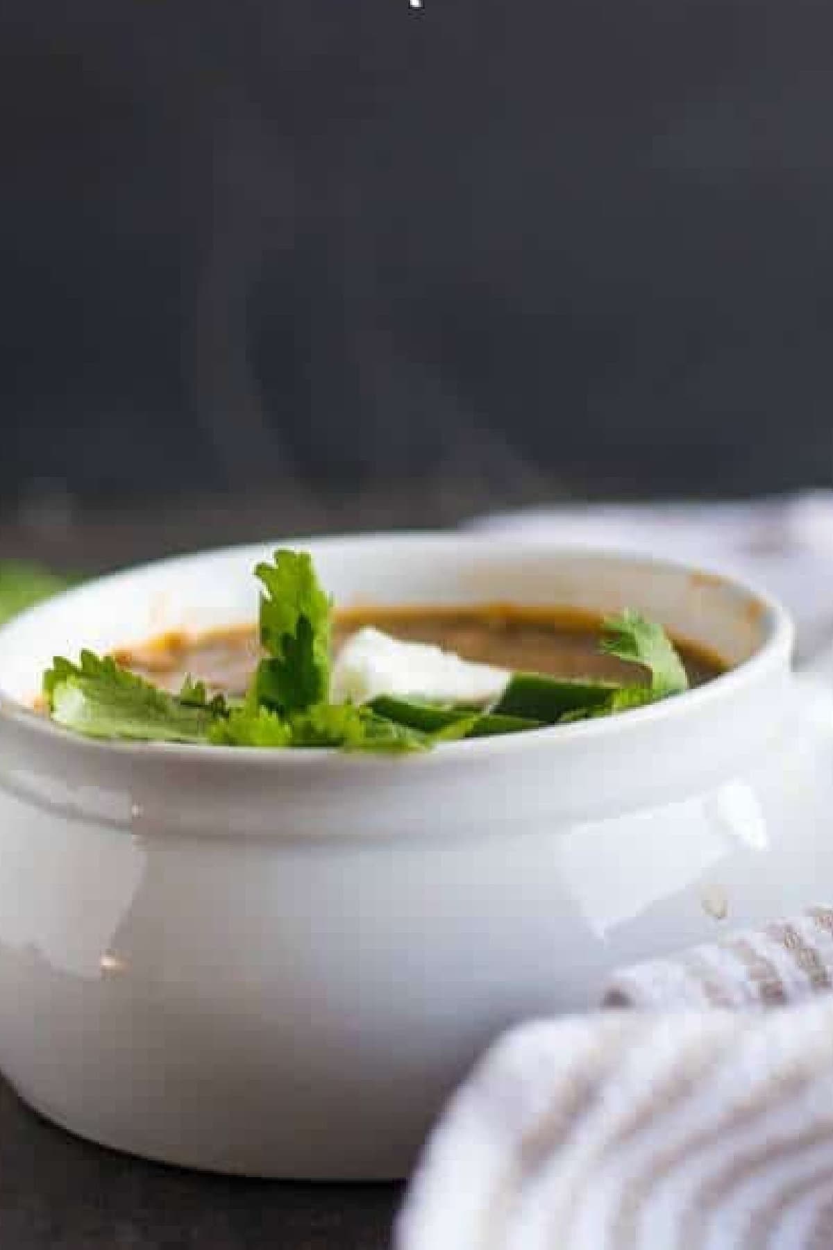 Side view of lentil soup in a white bowl.