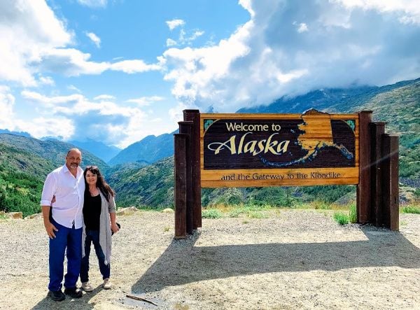 A Welcome to Alaska sign with Marye Audet-White and Marc White