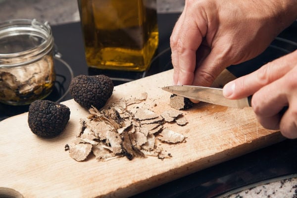 hands slicing truffles on a cutting board.