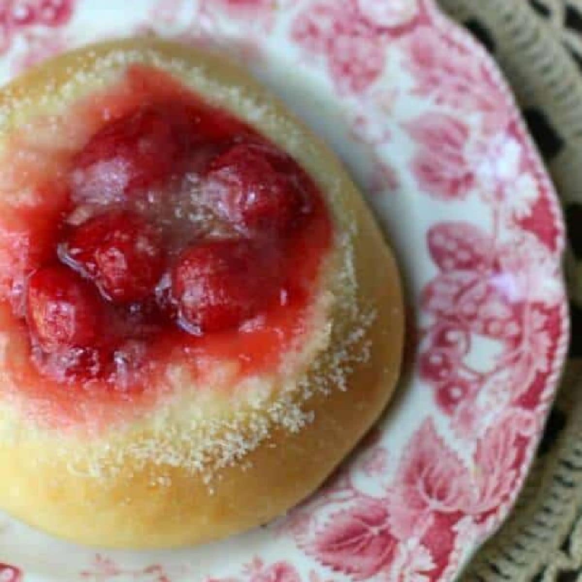 Overhead view of a cherry kolache on a red and white plate.