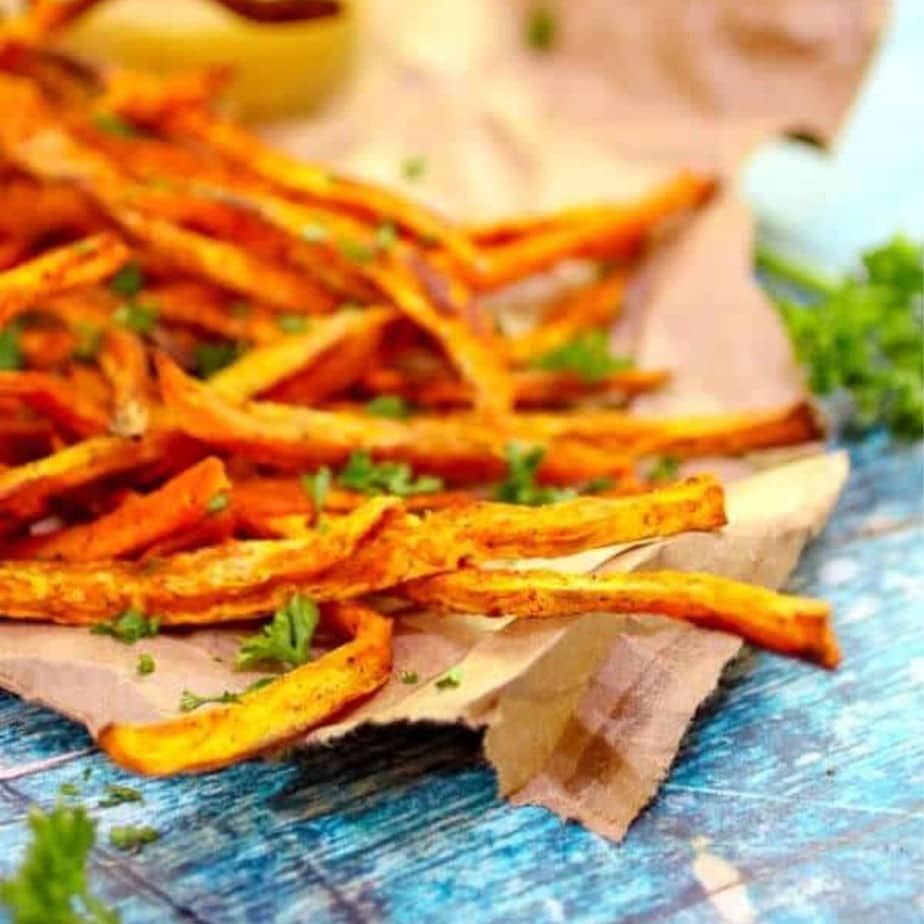 close up of sweet potato fries on a blue table.