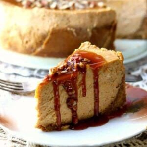 Slice of pumpkin cheesecake covered with caramel sauce and sprinkled with pecans.