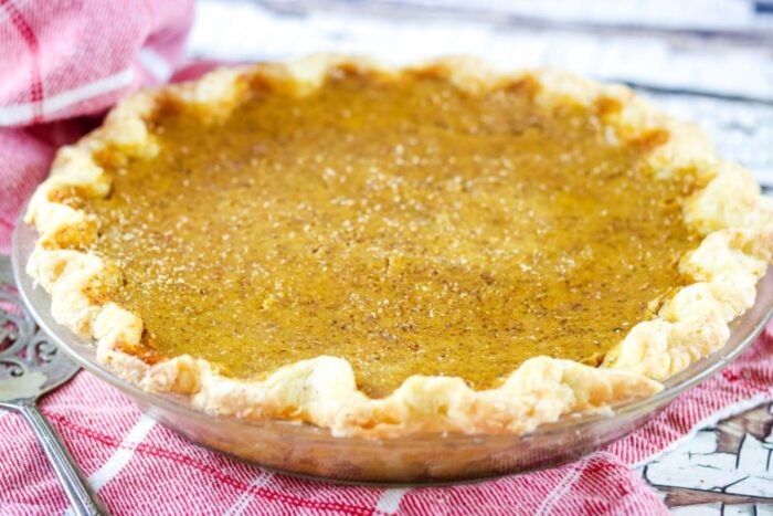 Whole, uncut butternut squash pie cooling on a counter.