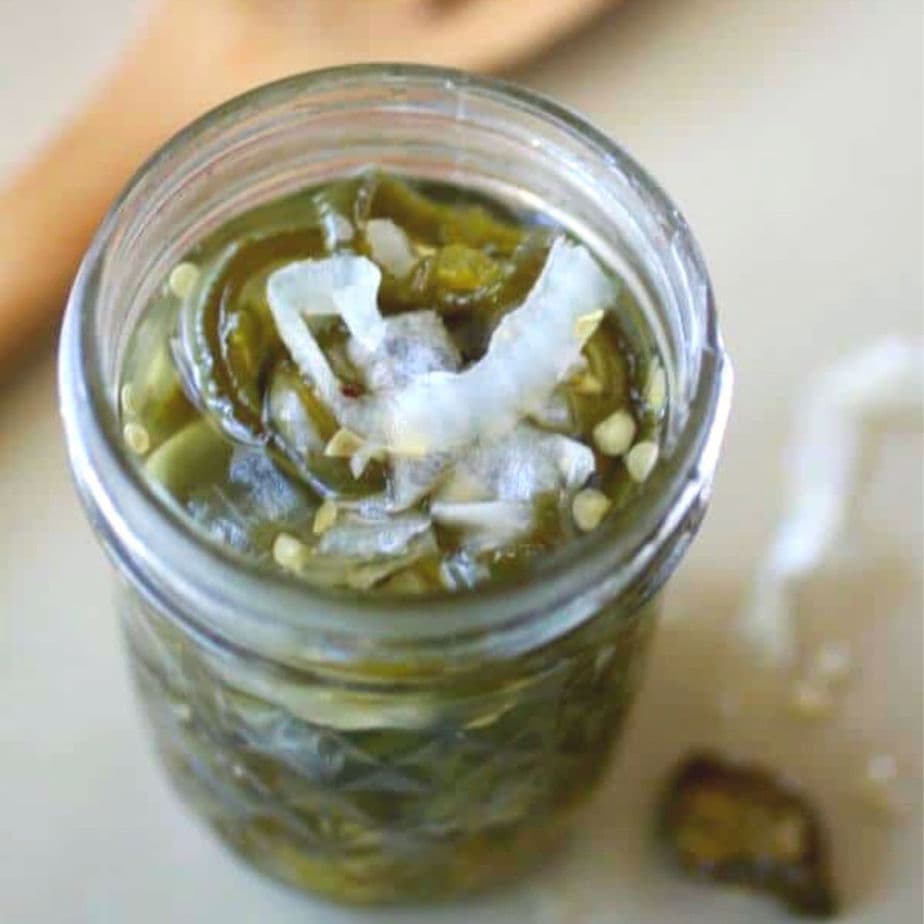 Top view of an open jar of candied jalapenos.