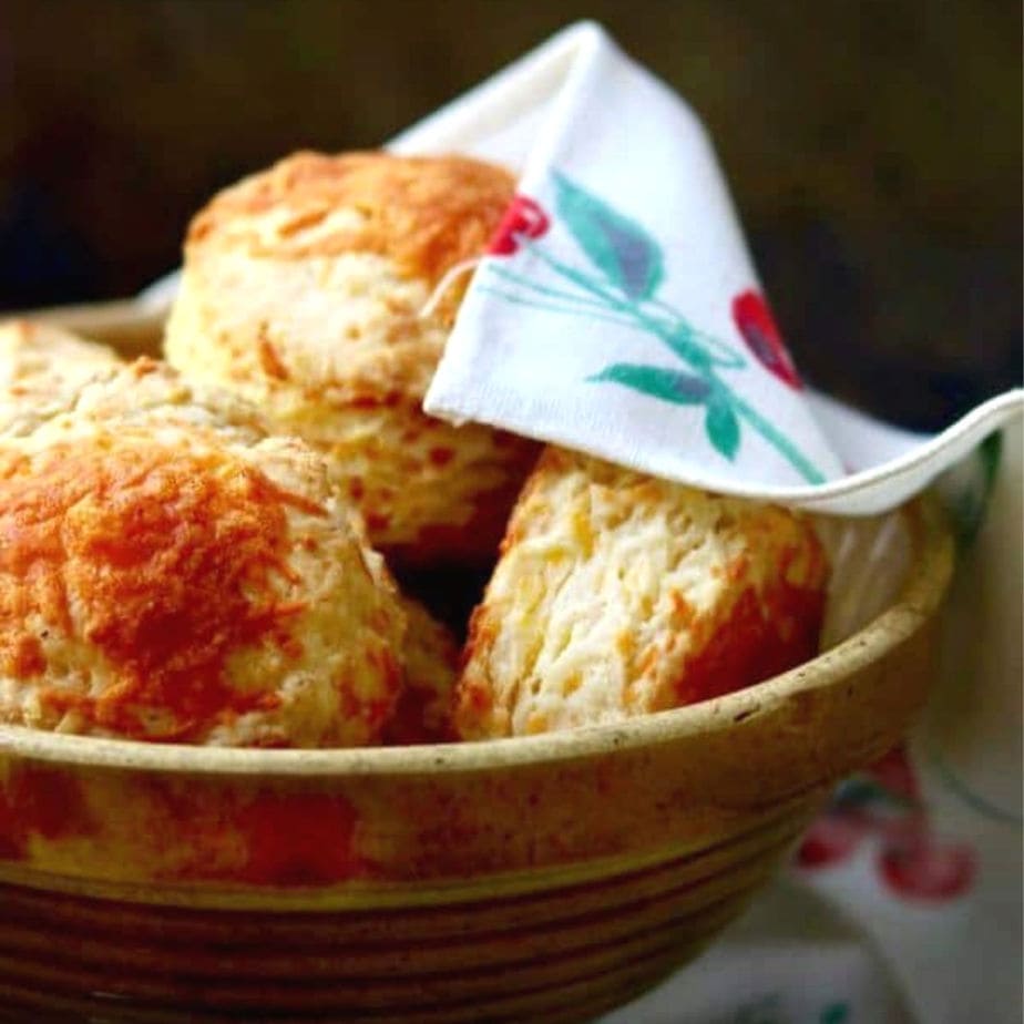Big, fluffy, flaky cheese biscuits in a bowl.