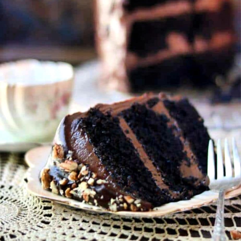 Slice of 3 layer chocolate cake on its side on a plate.