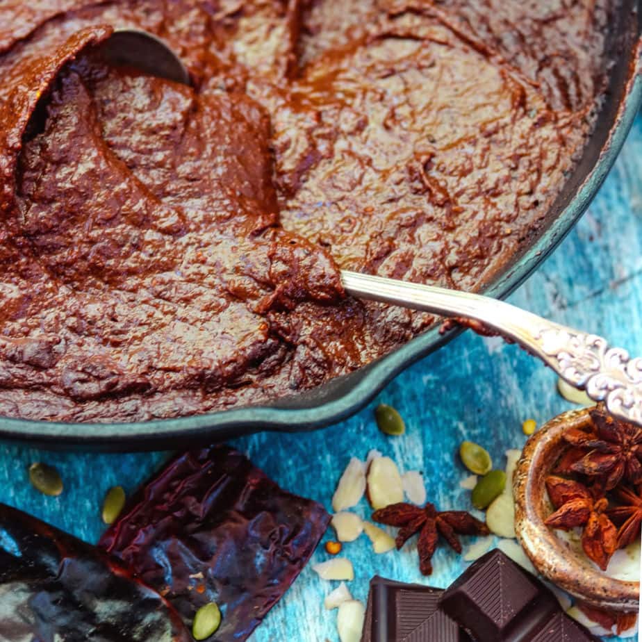 Mole sauce in an iron skillet with a silver ladle