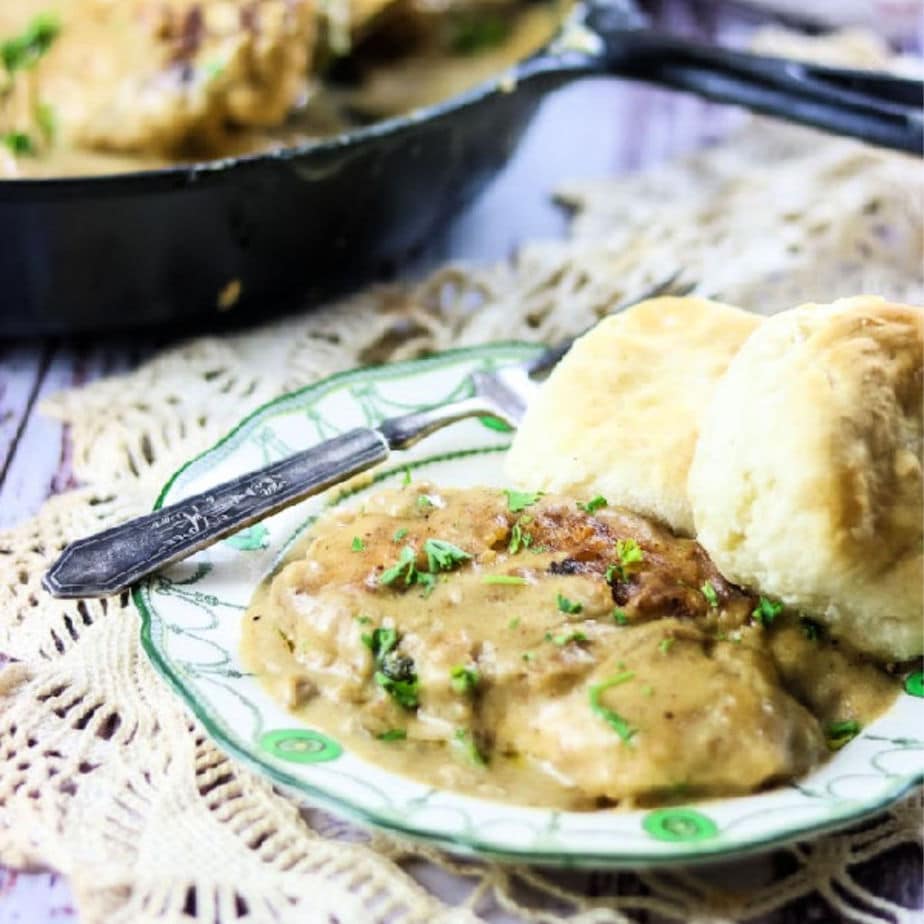 Smothered Chicken with gravy on a green and white plate illustrating the final dish