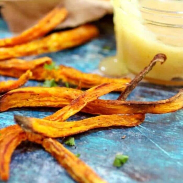 Bright orange sweet potato fries on a blue background.