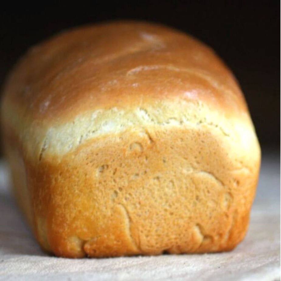 Baked loaf of homemade white bread, uncut.