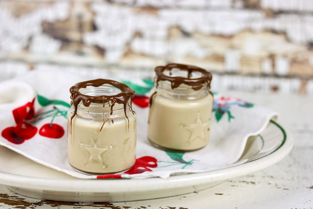 Two whiskey shot glasses with melted chocolate on the rims.