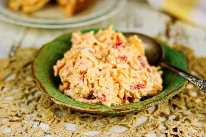 Pimento cheese in a green bowl with a serving spoon.