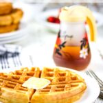 Buttermilk waffle on a plate with syrup nearby. Text overlay for Pinterest.