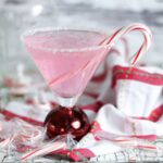 Pink peppermint martini with a candy cane garnish.