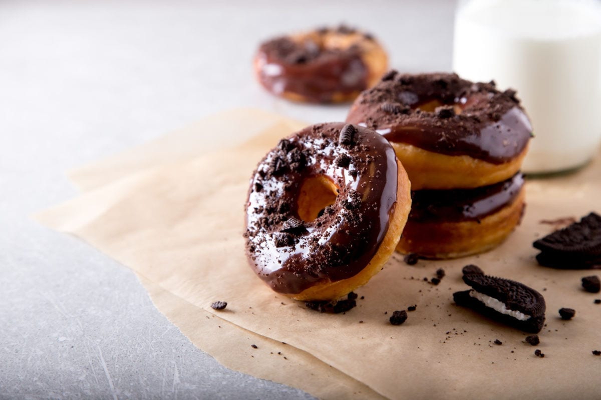 Chocolate glazed donuts stacked on a napkin.