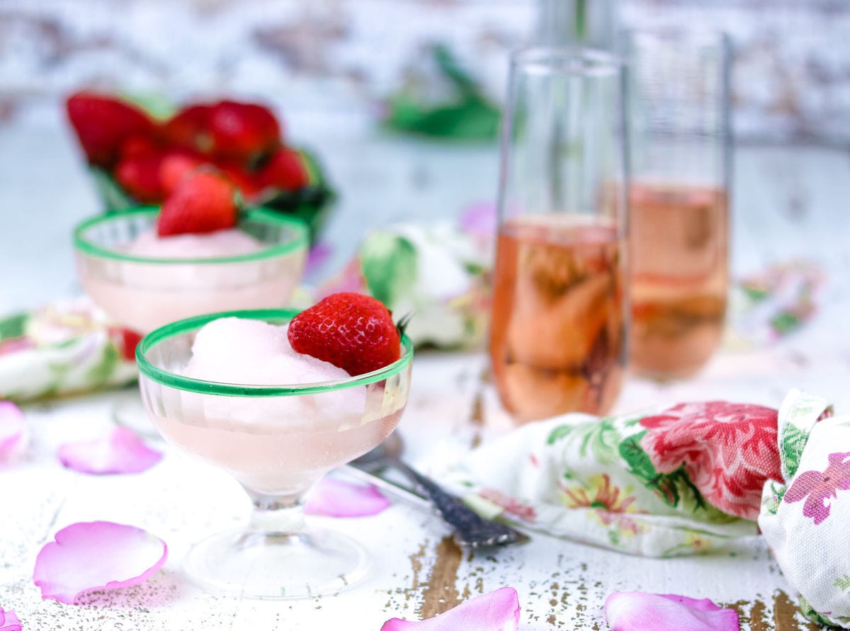 Finished pink wine sorbet garnished with berries. Two glasses of wine are in the background.