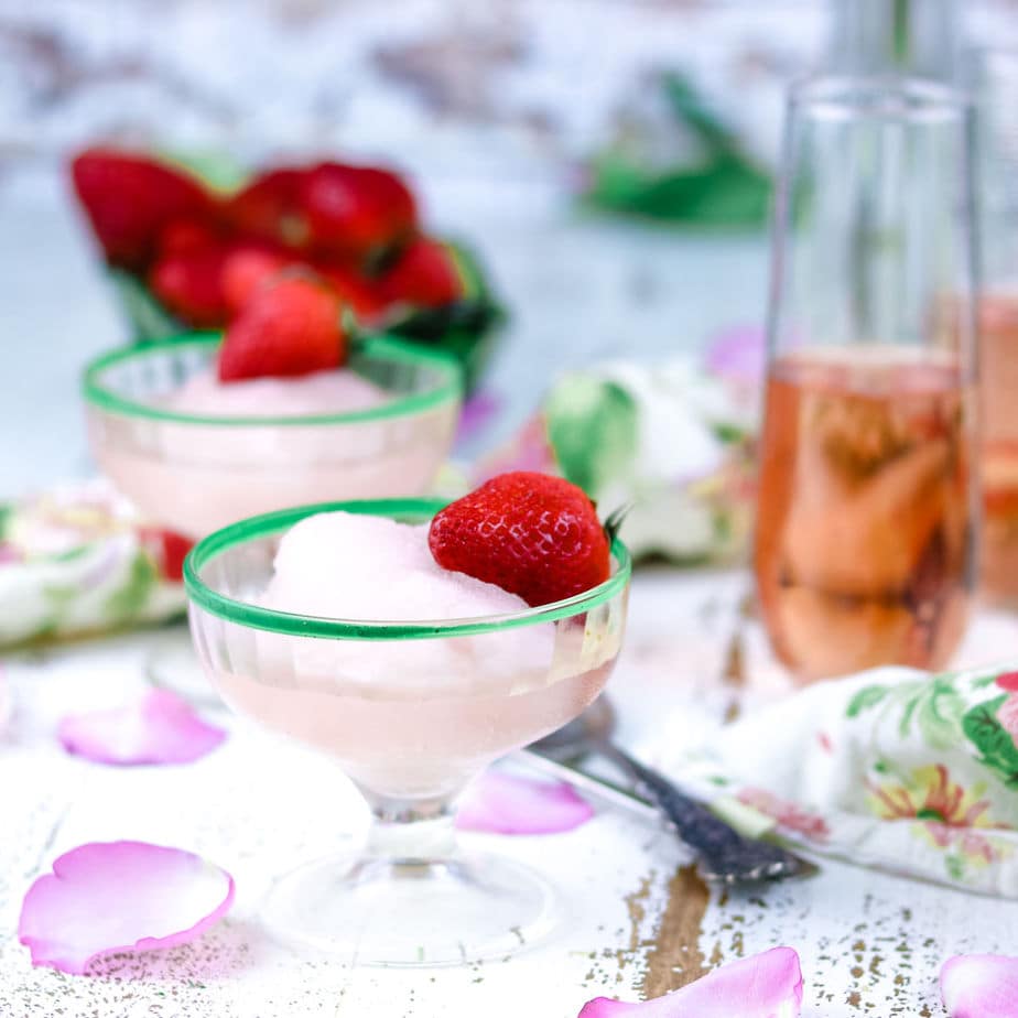 Pink rose moscato sorbet in small sherbet glasses garnished with strawberries.