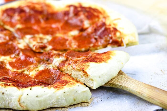 Closeup of finished pizza with slice removed.