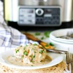 Finished hamburger steak covered in gravy on a plate in front of the slow cooker.