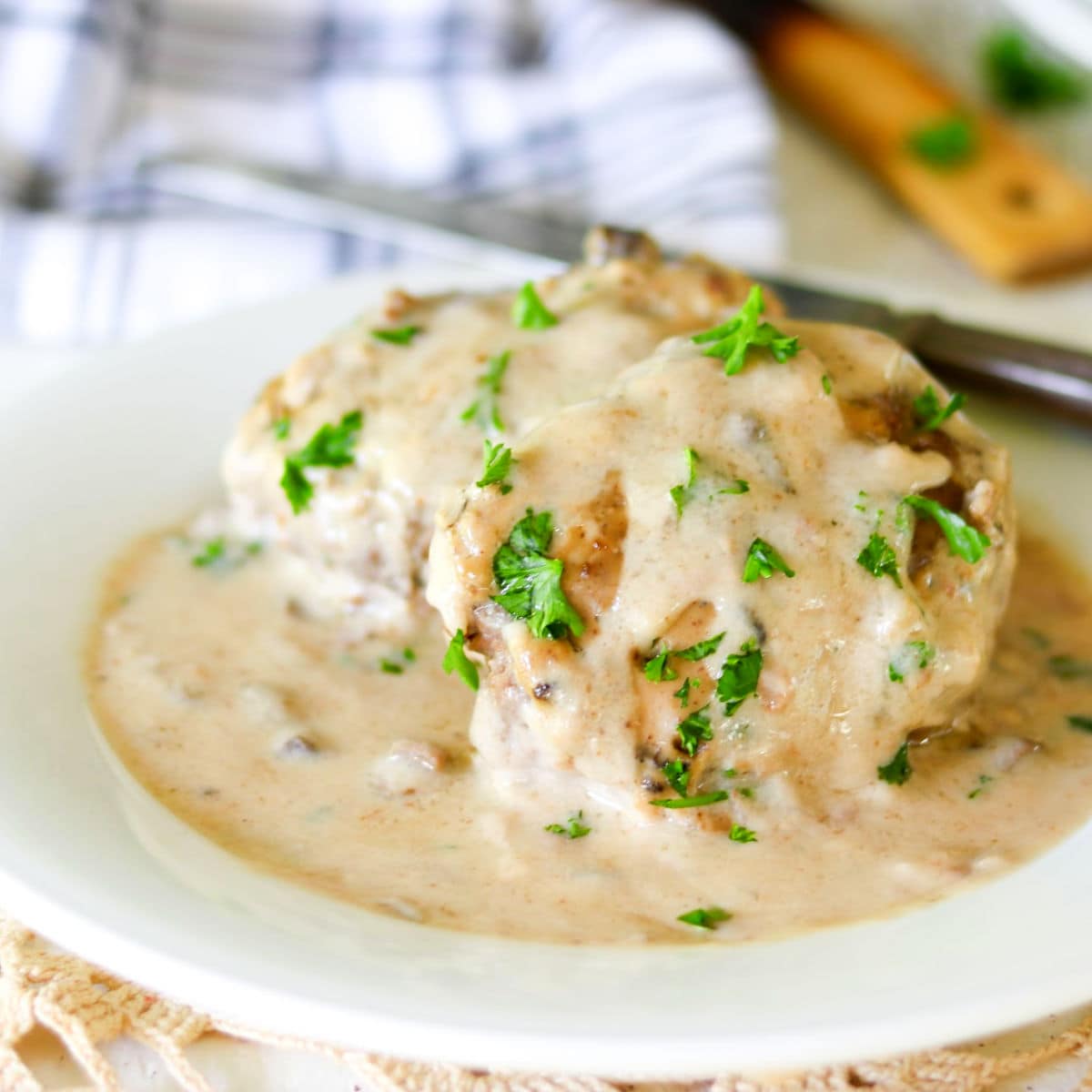 Closeup of salisbury steak covered in creamy gravy on a white plate.