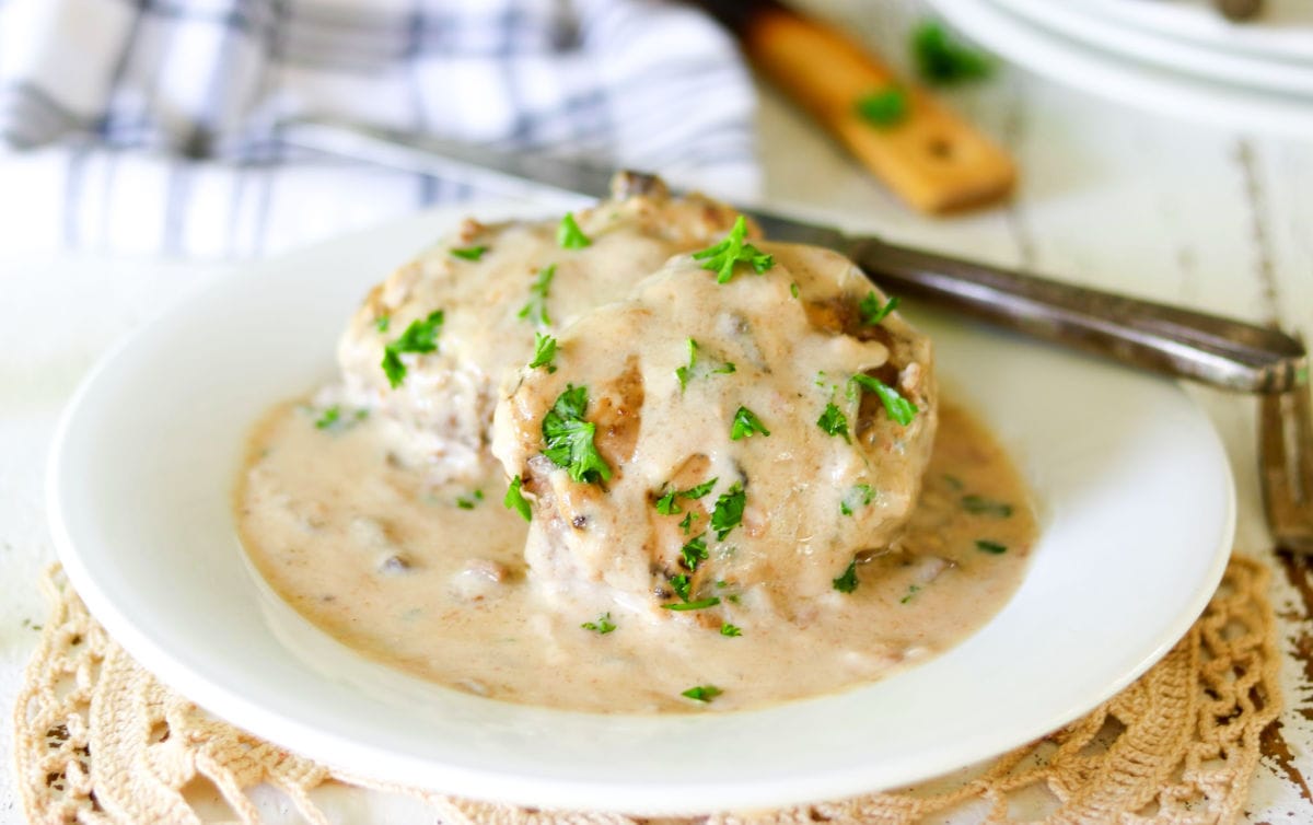 Hero image of the salisbury steak finished and on a white plate. It's garnished with green parsley.