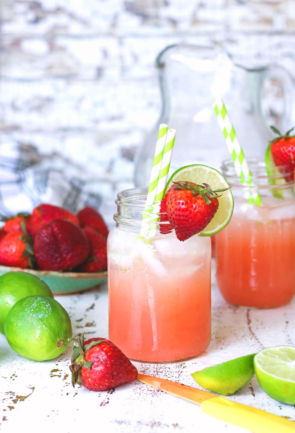 Closeup of strawberry punch cocktail with strawberries and limes on the wooden counter.