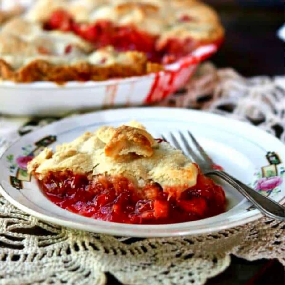 Slice of pie on a white plate. Whole pie in background.