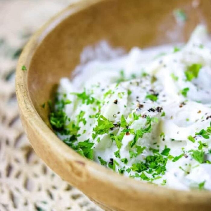 Cucumbers in sour cream in a yellow-ware bowl.