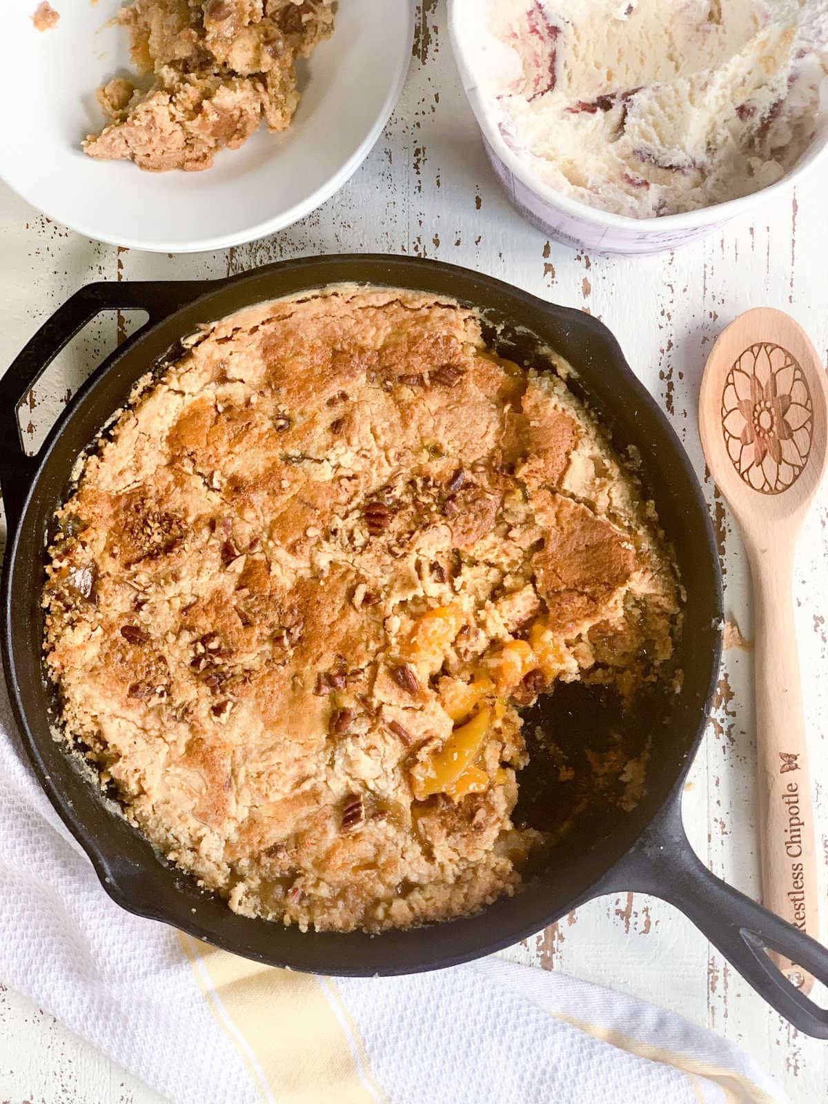 Top view of the peach dump cake in an iron skillet with a serving removed.