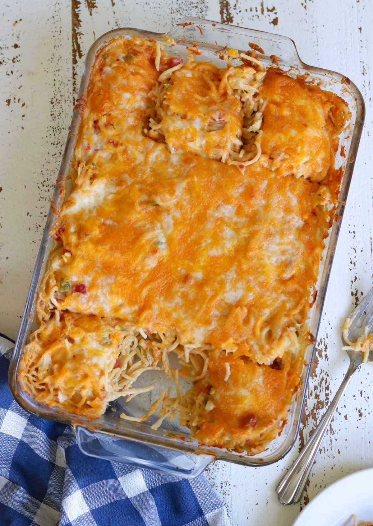 A baking dish with finished chicken spaghetti in itshowing the top of the casserole - one serving is removed.