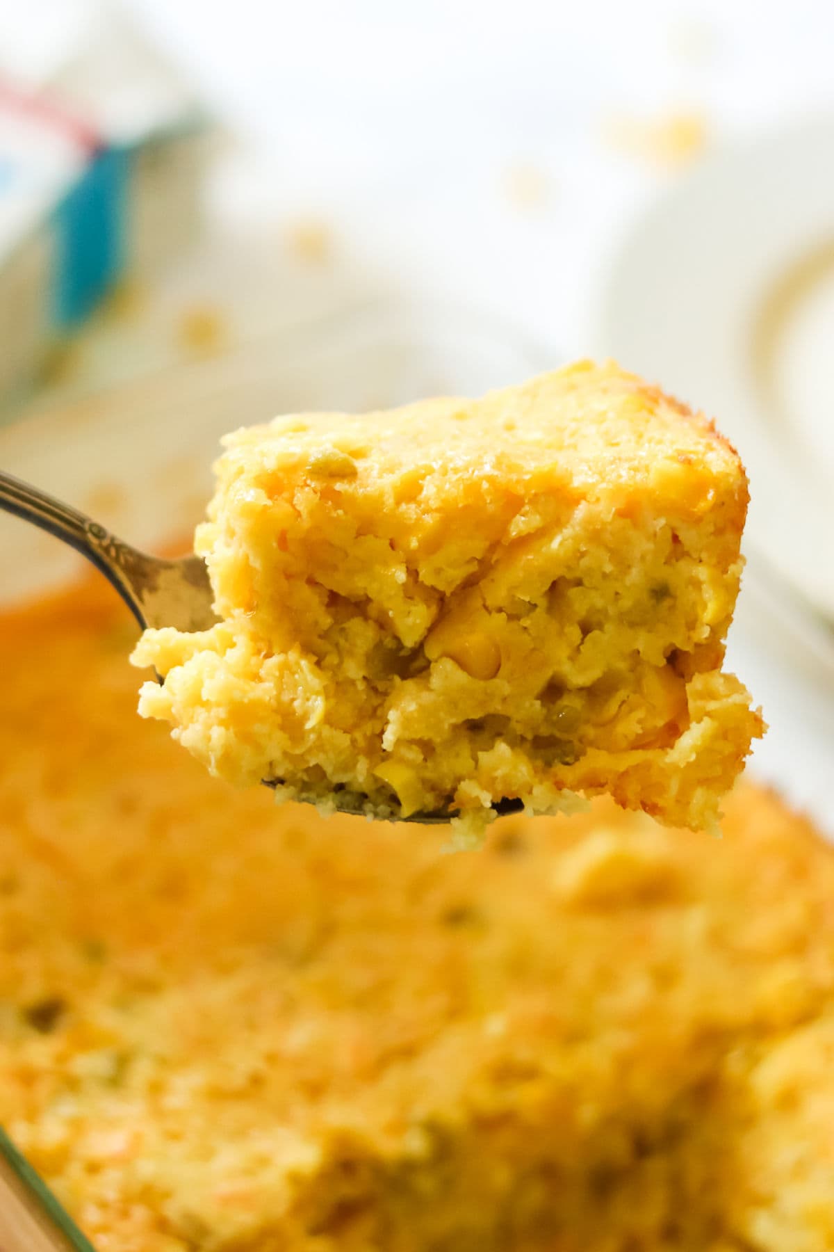 A serving of creamy corn casserole is lifted from the dish.