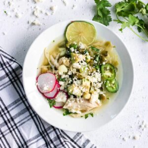 Overhead view of pozole in a white bowl.