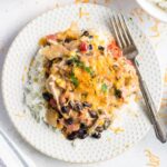 Overhead shot of finished fiesta chicken on a white plate with a fork to the side. Feature Image.