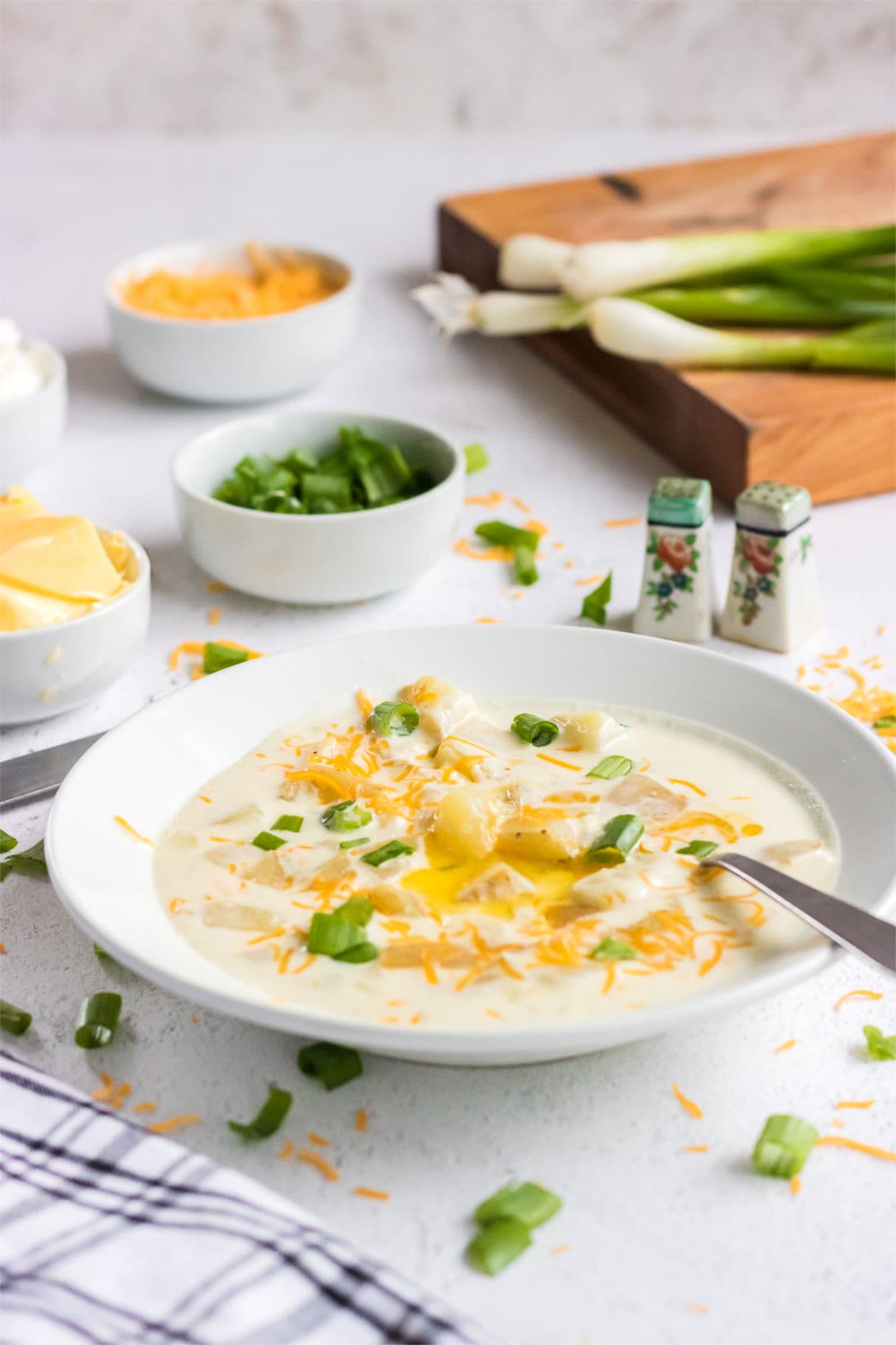 A bowl of creamy soup garnished with cheese and green onion.