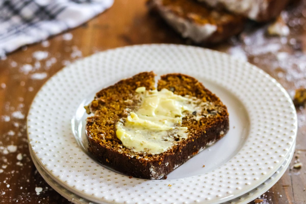 A slice of pumpkin spice bread with butter spread on top.