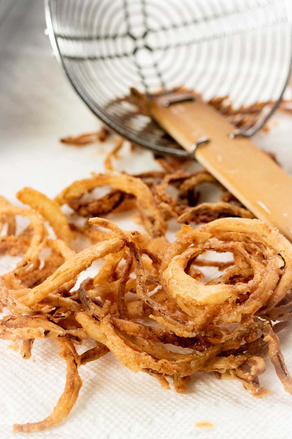 Closeup of finished onions draining on paper towel.