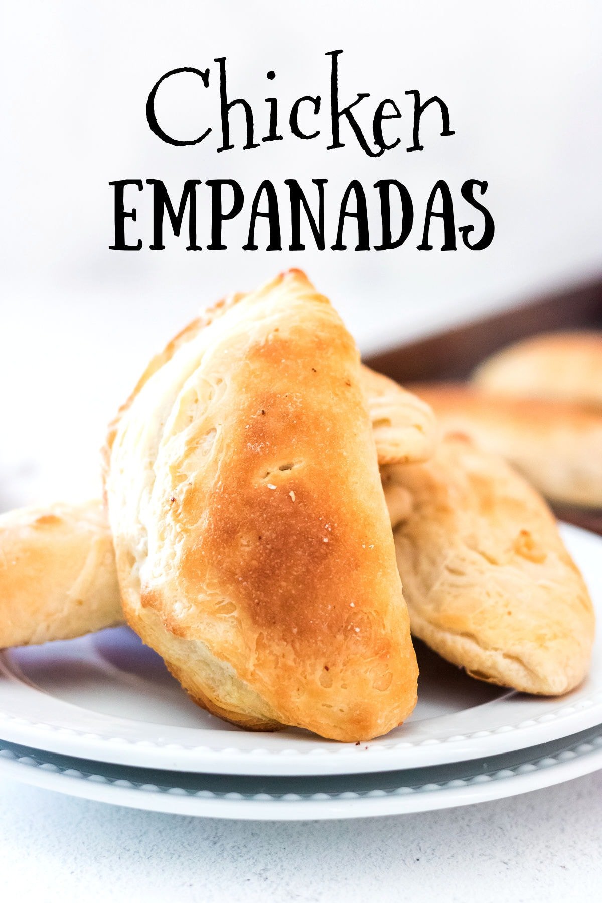 A white plate with baked empanadas stacked on the top.
