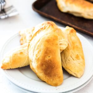 Empanadas piled on a plate.