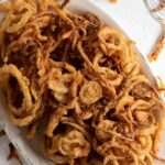 Overhead shot of fried onions on a platter with text overlay for Pinterest.