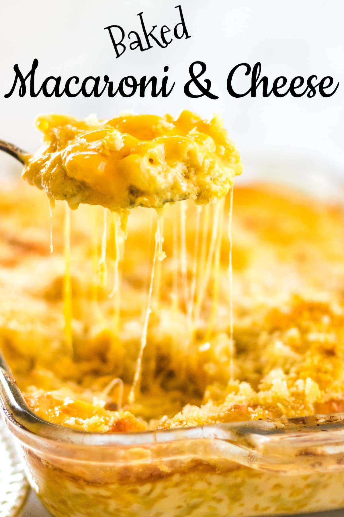 A serving of macaroni and cheese being remove from a pan with gooey cheese strings hanging down. Title text overlay.