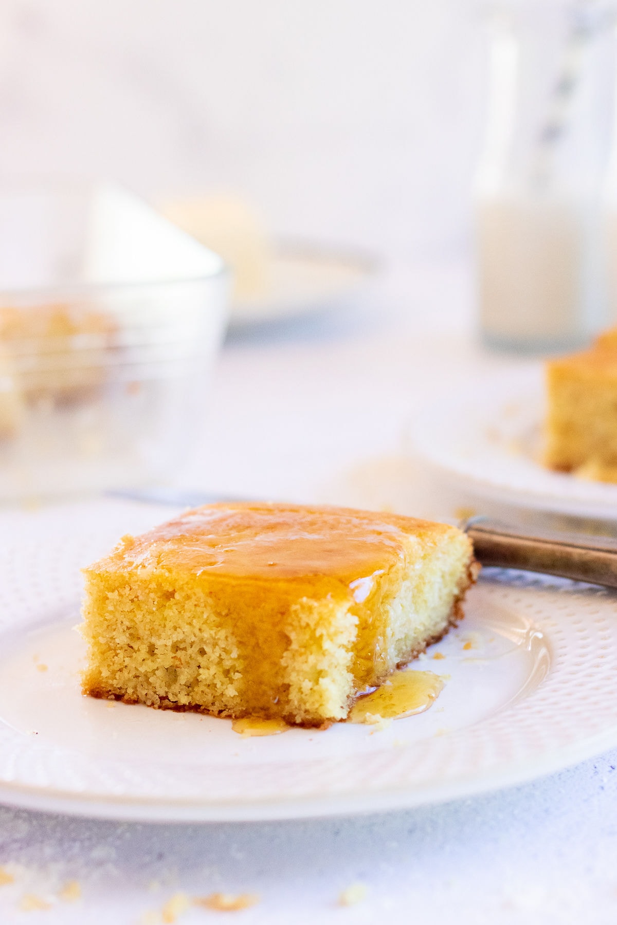 Square of buttermilk cornbread with honey dripping down the sides.