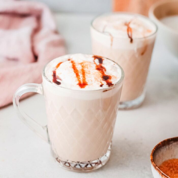 Closeup of two lattes in glass coffee cups.