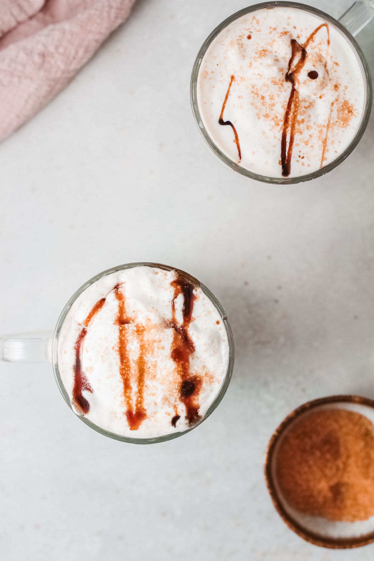 Overhead view of creamy coffee lattes with whipped cream.