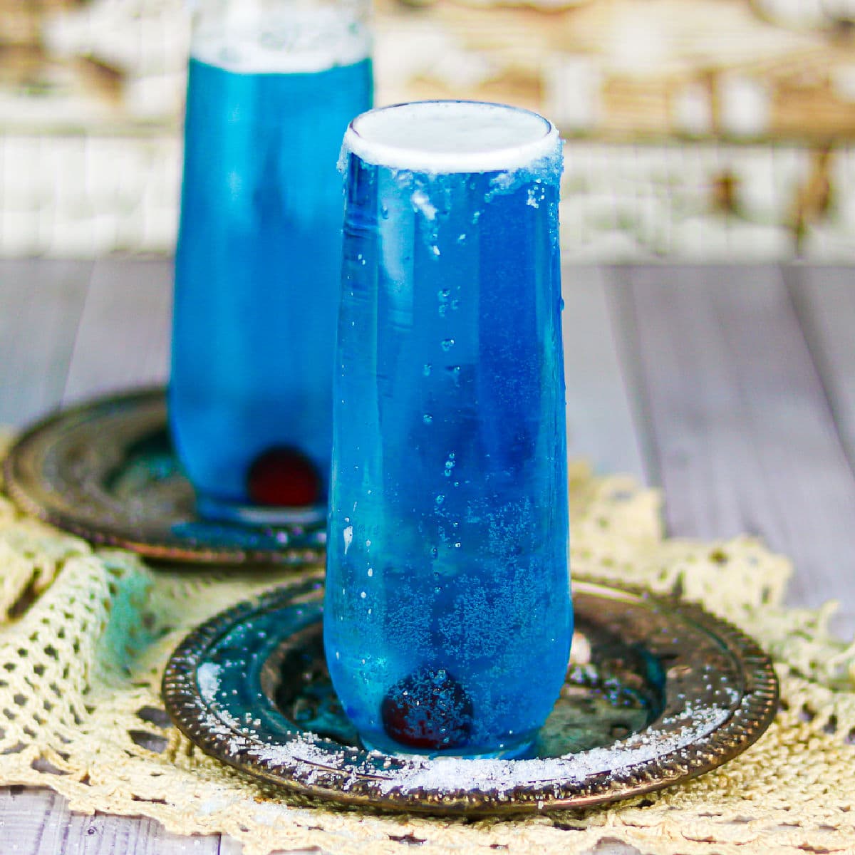 Two dark blue cocktails in champagne flutes.