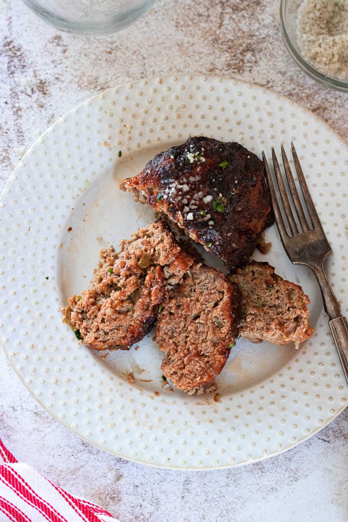 Slices of meatloaf on a plate with a fork to the side.